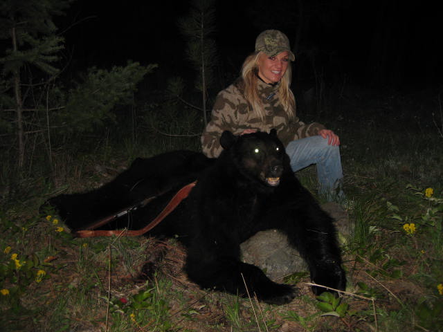 A girl sitting near a black bear