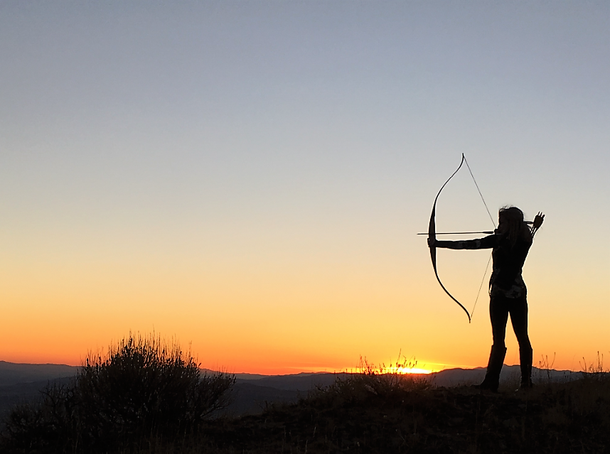 A person doing archery with a beautiful sunset