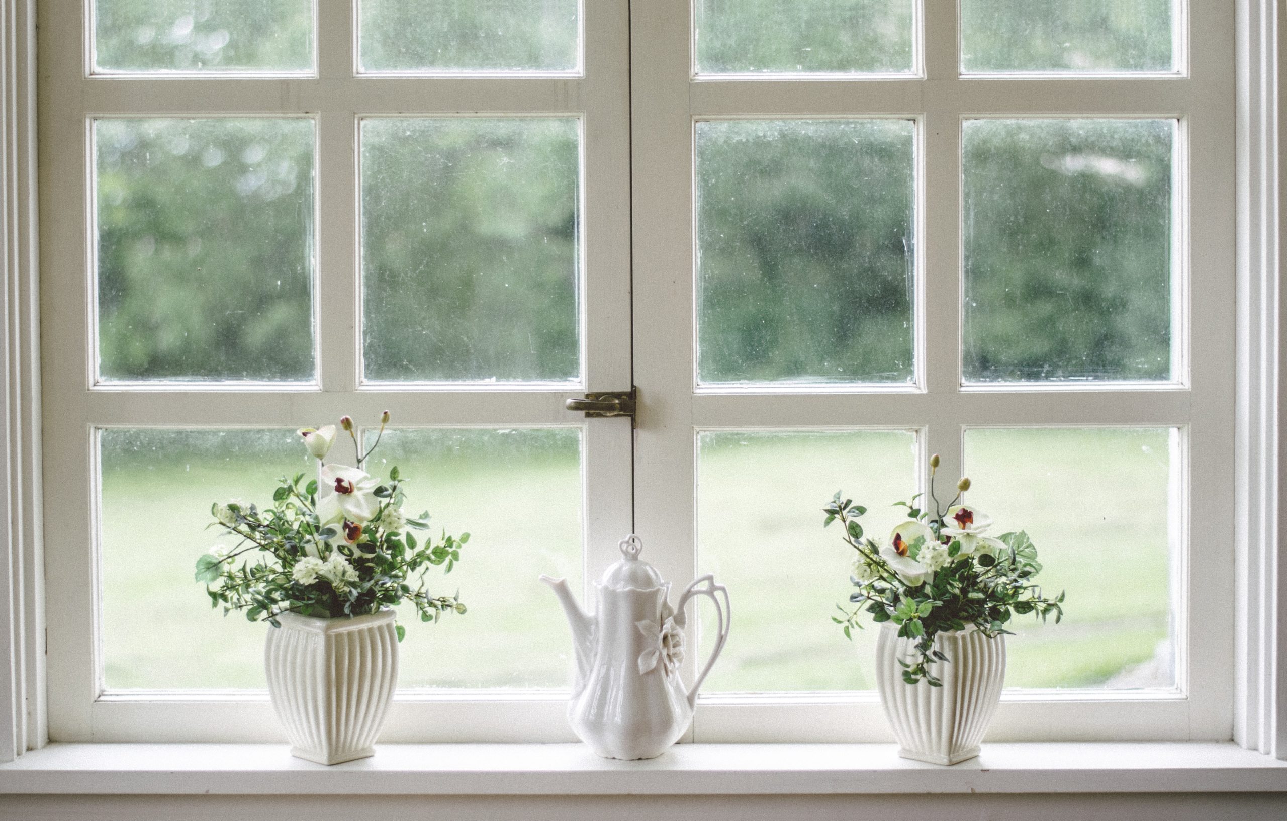 A window along with two flower pots and a tea pot