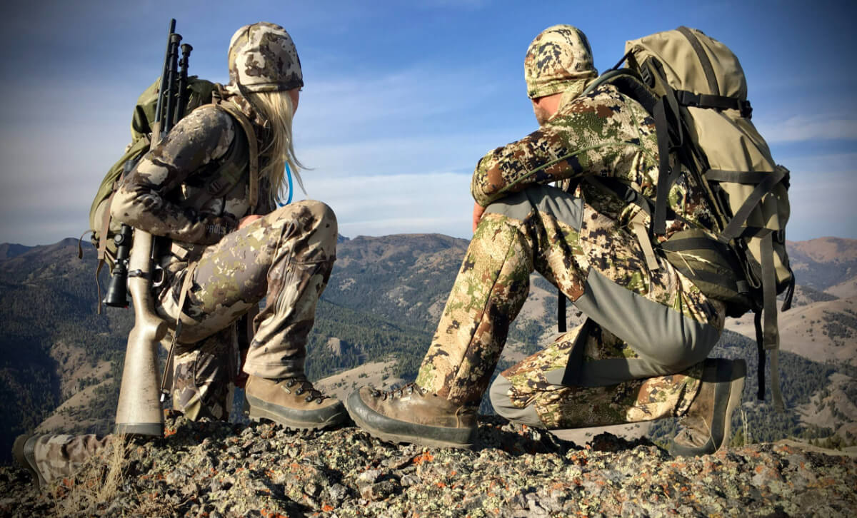 Two persons along with a gun sitting on mountain edge
